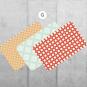 Könnte beinhalten: Drei rechteckige Tischsets mit verschiedenen Mustern. Das erste Tischset hat ein welliges orange-weißes Muster. Das zweite Tischset hat ein weiß-hellblaues Muster mit einem Blumendesign. Das dritte Tischset hat ein rot-weißes Punkte-Muster.