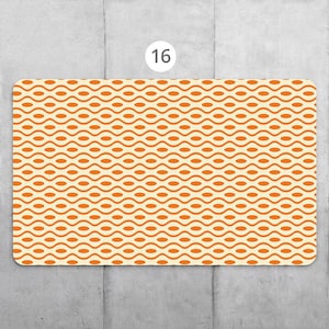 Könnte beinhalten: Orangefarbener und weißer Platzdeckchen mit einem welligen Muster. Das Platzdeckchen hat die Nummer "16" aufgedruckt.