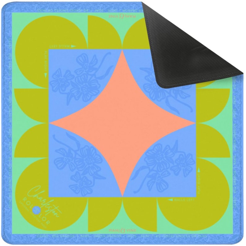 K&ouml;nnte beinhalten: Eine farbenfrohe, gemusterte Matte mit blauem Rand. Das Design zeigt eine zentrale pfirsichfarbene Raute auf einem blauen Quadrat, umgeben von blauen Blumenmustern und gelb-gr&uuml;nen Halbkreisen. Der Text "Charleston" ist sichtbar.