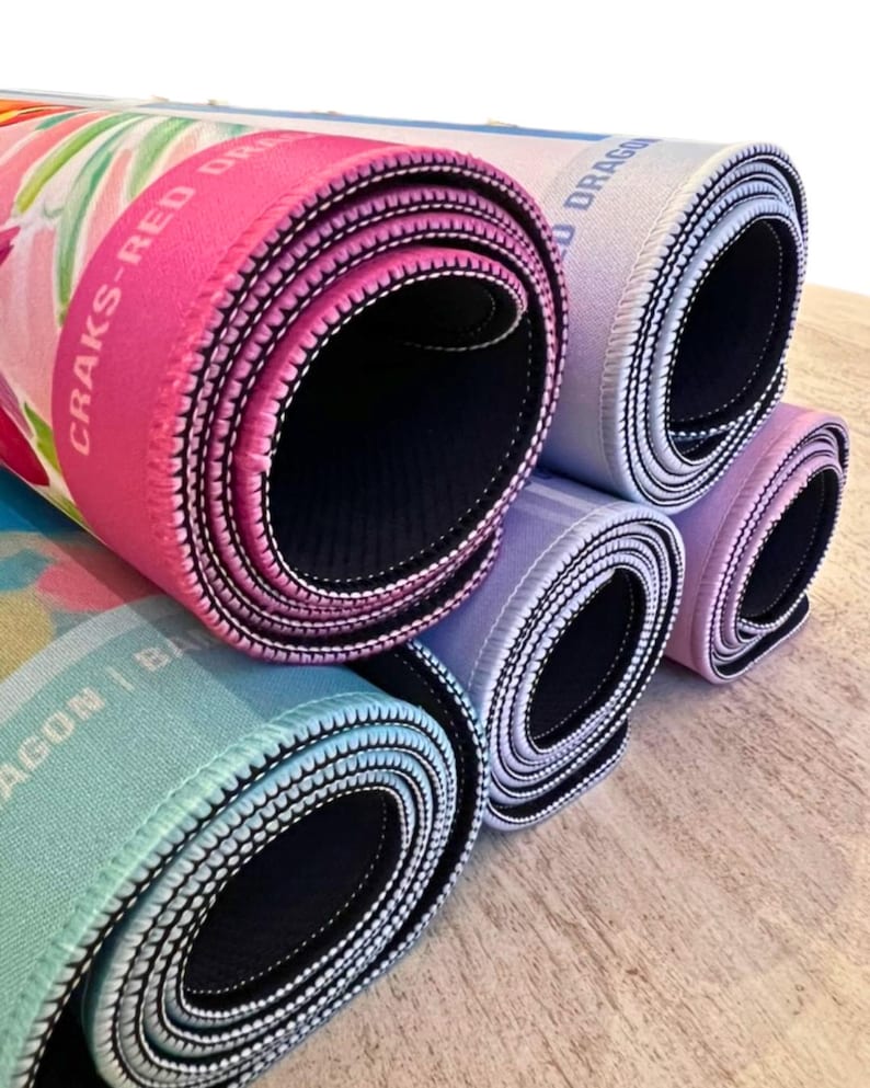 May include: Rolled-up mouse pads in various colors, including pink, blue, and purple. The pads have a black interior and white stitching around the edges. The text "CRAKS-RED DRAGON" is visible on one of the pads.