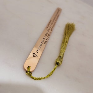 May include: A gold bookmark with a heart and the text "01111001 01101110 01100111 01110011 01110100 01100101 01110010 01110100" engraved on it. The bookmark has a green tassel.