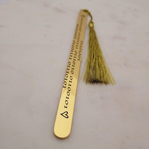 May include: Gold bookmark with a tassel and the words "LOOOTOOO LIIOOTO LOOTOOO LIIOOTO LOOTOOO LIIOOTO LOOTOOO" engraved on it.