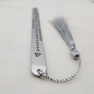 May include: Silver bookmark with a heart and a string of binary code. The bookmark has a silver tassel.