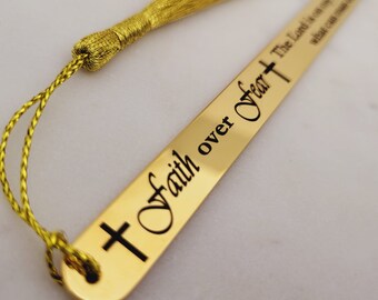 May include: Gold bookmark with a tassel. The bookmark has a cross and the words "Faith over Fear" engraved on it.