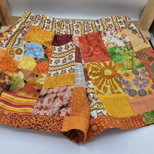 May include: Patchwork shorts in a variety of warm colors, including orange, yellow, and brown. The shorts feature a mix of floral, geometric, and abstract patterns. The waistband is elasticized.