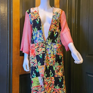 May include: A long, patchwork cardigan with a V-neckline and long sleeves. The cardigan is made of a variety of fabrics in different colors and patterns, including red, green, yellow, blue, and black. The cardigan has a button closure at the front.