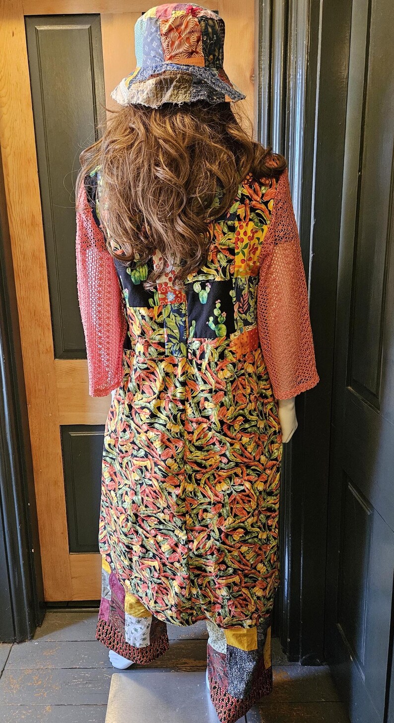 May include: A patchwork bucket hat and a long-sleeved dress featuring a vibrant cactus and chili pepper print. The dress has coral-colored mesh sleeves and is paired with patchwork trousers in various patterns and colors, including yellow and brown.