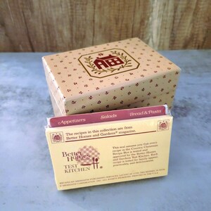 May include: A set of recipe cards in a box with a Better Homes and Gardens logo. The cards are divided into three categories: Appetizers, Salads, and Bread & Pasta. The box is beige with a red house design and the text "Better Homes and Gardens" on the front.