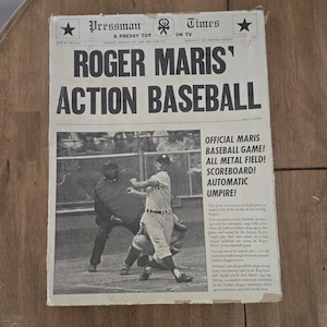 May include: A vintage board game box featuring a black and white photo of baseball player Roger Maris in action. The box is titled "Roger Maris' Action Baseball" and features the text "Official Maris Baseball Game! All Metal Field! Scoreboard! Automatic Umpire!"