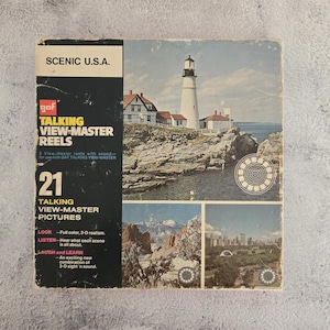May include: A vintage box of 21 GAF Talking View-Master pictures featuring scenic views of the United States. The box features a lighthouse on a rocky coast, a mountain range, and a city skyline. The text on the box reads "Scenic U.S.A." and "21 Talking View-Master Pictures".