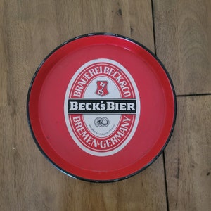 Vintage Beck's Bier | Czerwona okrągła metalowa taca | Wyprodukowano w Niemczech | Jaskinia mężczyzny | Den | Bar | Prezent | Alkohole | Naczynia barmańskie