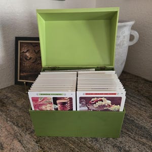 Peut inclure: Une boîte à recettes en plastique vert lime avec un couvercle ouvert, contenant deux rangées de fiches blanches. Les cartes avant présentent des photographies culinaires colorées et les étiquettes Seasonal Favorites et Snacks Around the Clock.