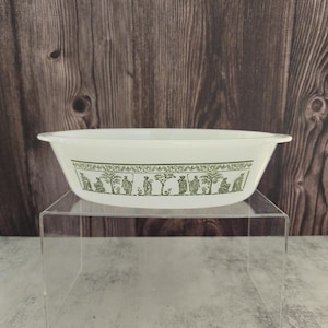 May include: White oval baking dish with a green and white pattern of stylized figures and trees around the rim.