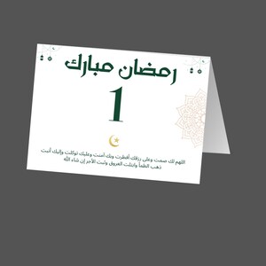 May include: A white card with green text that reads "Ramadan Mubarak" and the number "1". The card also features a crescent moon and a gold mandala design. The text below the number reads "Allahumma laka sumtu wa ala rizqika aftastu wa bika amantu wa alayka tawakkaltu wa ilaika anabtu. Dhaba al-zhama wa abtalat al-uruq wa thabat al-ajr in shaa Allah."