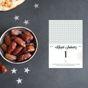 May include: A bowl of dates, a traditional food eaten during Ramadan, with a card that says "Ramadan Mubarak 1" in Arabic. The card also includes a prayer in Arabic.