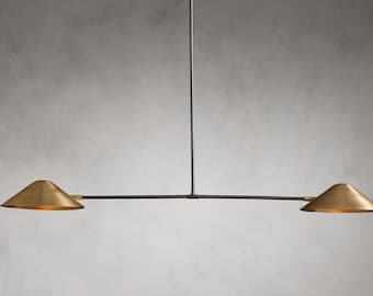 Può includere: Un apparecchio di illuminazione in metallo nero con due paralumi dorati. L'apparecchio ha un braccio lungo e dritto che si estende dal centro.