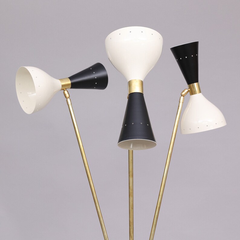 Pu&ograve; includere: Una lampada da terra in ottone con tre bracci regolabili e paralumi a forma di cono neri e bianchi. La lampada ha un design moderno di met&agrave; secolo.