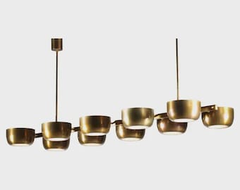 May include: A modern, brass-toned chandelier with eight bowl-shaped light fixtures. The lights are suspended from a horizontal bar and a central vertical rod. The design is minimalist and elegant, suitable for various interior styles.