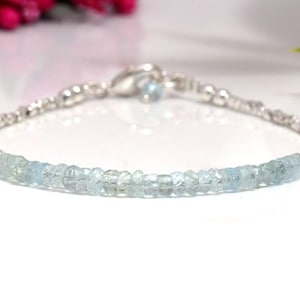 Op de afbeelding: Een delicate zilveren armband met een rij lichtblauwe aquamarijn kralen.