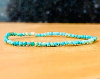 May include: A turquoise gemstone bracelet with small, faceted beads.