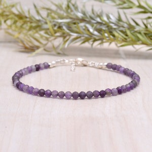 May include: A delicate amethyst gemstone bracelet with a silver clasp. The bracelet is made with small, round beads and is a beautiful shade of purple.