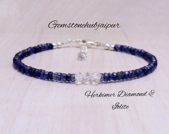 May include: A silver bracelet with blue iolite and clear Herkimer diamond beads. The bracelet has a silver clasp and a small silver charm.