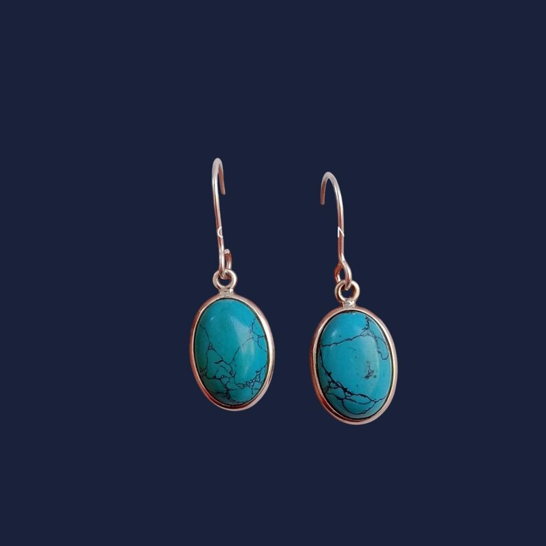 May include: A pair of silver dangle earrings with oval turquoise stones.