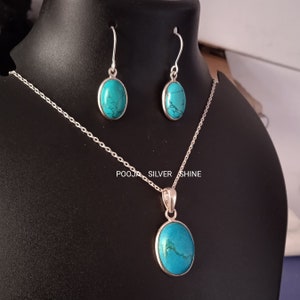 May include: A turquoise gemstone pendant necklace and matching earrings set. The pendant and earrings feature oval-shaped turquoise stones set in silver.