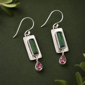 Puede incluir: Un par de pendientes colgantes de plata con una placa rectangular de plata engastada con una turmalina verde vertical de corte baguette. Una pequeña piedra preciosa rosa en forma de pera cuelga de la base de cada placa rectangular.