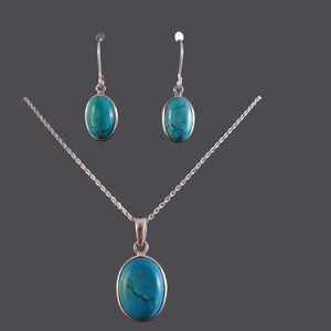 May include: A silver necklace and earrings set with oval turquoise stones.