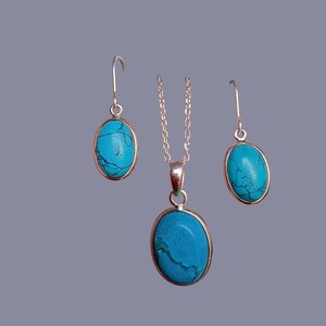 May include: A turquoise gemstone pendant necklace and matching earrings set. The oval-shaped stones are set in silver.