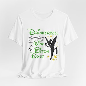 May include: White t-shirt with the text "Drinkerbell Running on Wine & Bitch Dust" in green and black. A black silhouette of a fairy holding a wine glass and bottle is also featured.