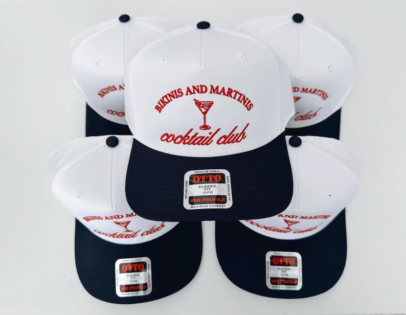 May include: Five white and blue baseball caps with the text "Bikinis and Martinis cocktail club" and a martini glass graphic in red. The caps have a navy blue brim and a white crown.