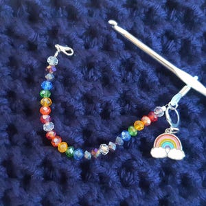 May include: A rainbow-colored beaded stitch marker with a rainbow charm attached to a silver crochet hook.