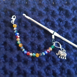 May include: A colorful beaded stitch marker with an elephant charm attached to a silver crochet hook.