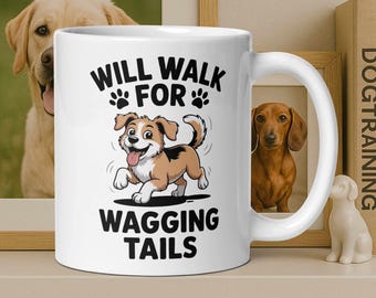 May include: White ceramic mug with the text "WILL WALK FOR WAGGING TAILS" and a cartoon dog illustration. The dog is brown, white, and black with its tongue sticking out. The mug is on a white surface.