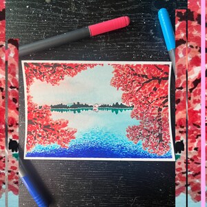 May include: A watercolor painting of a lake scene with red trees on either side of the lake. The lake is blue and the sky is light blue. The trees are painted in a stippled style.