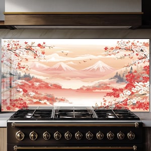 Könnte beinhalten: Eine dekorative Küchenrückwand mit einer japanischen Landschaft. Das Kunstwerk zeigt schneebedeckte Berge, Kirschblüten und einen pfirsichfarbenen Himmel. Die Rückwand ist über einem schwarzen und goldenen Gasherd angebracht und verleiht der Küche einen Hauch von Eleganz.