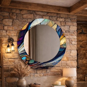 May include: A round mirror with a stained glass design in shades of blue, yellow, and purple hangs on a brick wall. A wooden console table with drawers and baskets sits below the mirror. A lamp and decorative items are on the table.