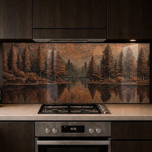 May include: A kitchen backsplash featuring a landscape painting of a forest and lake with reflections. The artwork has warm tones of brown and orange. The kitchen also includes a black kettle, a small plant, and a stainless steel oven.