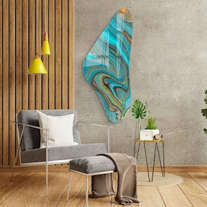 May include: Abstract wall art featuring a blue, gold, and green marbled design in an irregular, organic shape. The art is hanging on a gray concrete wall.