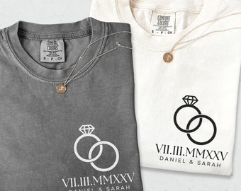 May include: Two gray and white t-shirts with a ring design and the text "VII.III.MMXXV DANIEL & SARAH" printed on them.