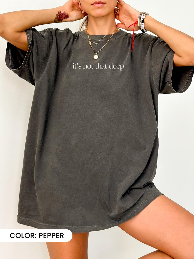May include: An oversized t-shirt in a dark grey colour with the text "it's not that deep" printed in white on the front.