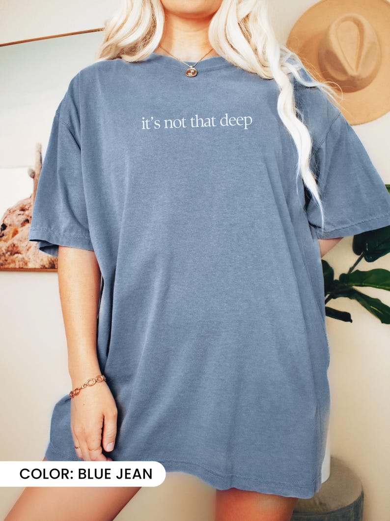 May include: An oversized t-shirt in blue jean colour with the text "it's not that deep" in white.