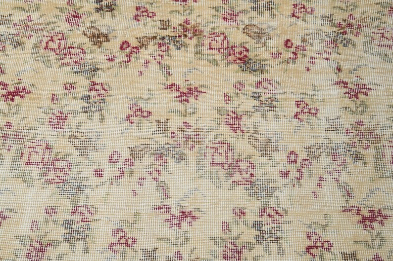 May include: A vintage rug with a cream background and a floral pattern in shades of pink, green, and brown.