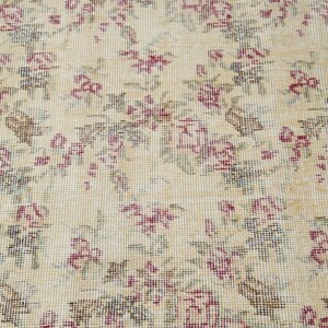 May include: A beige rug with a floral pattern in shades of pink and green. The rug has a woven texture and a delicate design.