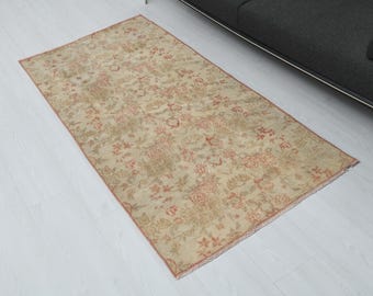 Puede incluir: Una alfombra rectangular de color beige y rojo con un patrón floral y un aspecto ligeramente desgastado. La alfombra está hecha de un material suave y tejido.
