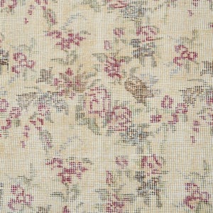 May include: A beige rug with a floral pattern. The flowers are pink and green and are woven into the rug.