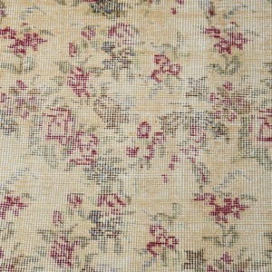 May include: Close-up of a beige fabric with a floral pattern. The fabric is woven with small, intricate details, creating a delicate and vintage aesthetic. The flowers are a pale pink color and are scattered throughout the fabric.