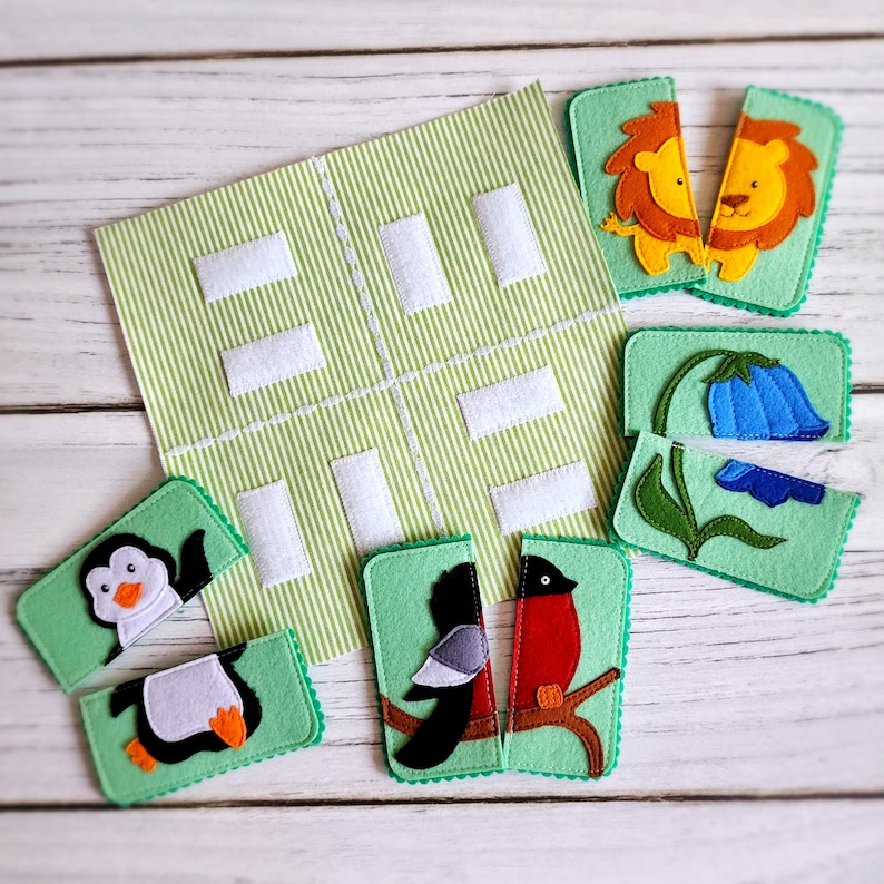 May include: A green felt board with white squares and a variety of felt animal and flower puzzle pieces. The pieces include a penguin, a bird, a lion, and a flower.